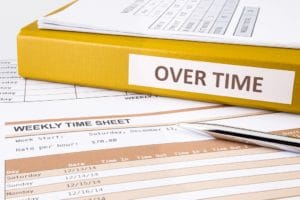 Overtime words on document binder place on blank weekly time sheets