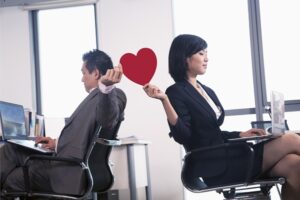 Co-workers sharing a paper heart for office romance