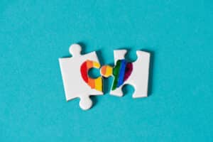 two pieces of a puzzle, which put together form a rainbow heart, on a blue background, depicting the lack of right of same-sex marriage or the divorce of same-sex couples