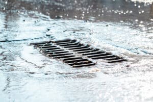 The grate of the storm sewer after the rain. The water drains into the storm drain. 