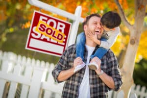 A father and son in front of a sold sign