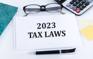 2023 tax laws text on a notebook on the table next to glasses, calculator, documents