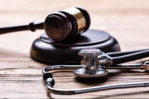 Close-up Of Stethoscope And Gavel Over Wooden Desk